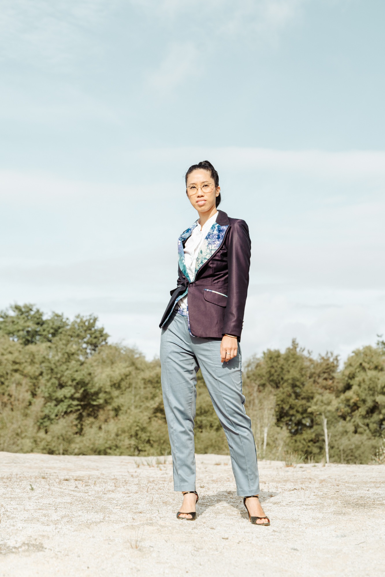 Veste prune aux revers imprimés portée avec un pantalon gris, collection Fusion