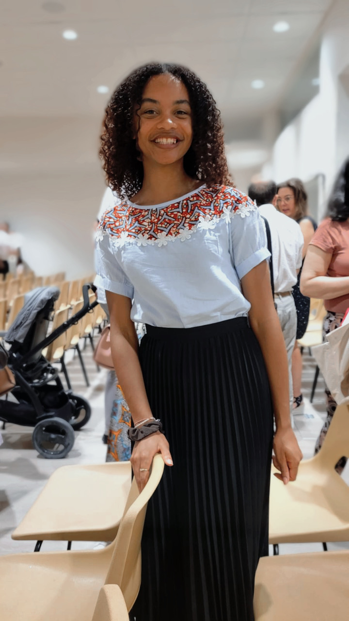 Femme portant une blouse bleu ciel brodée et une jupe noire Wax.by.Mona