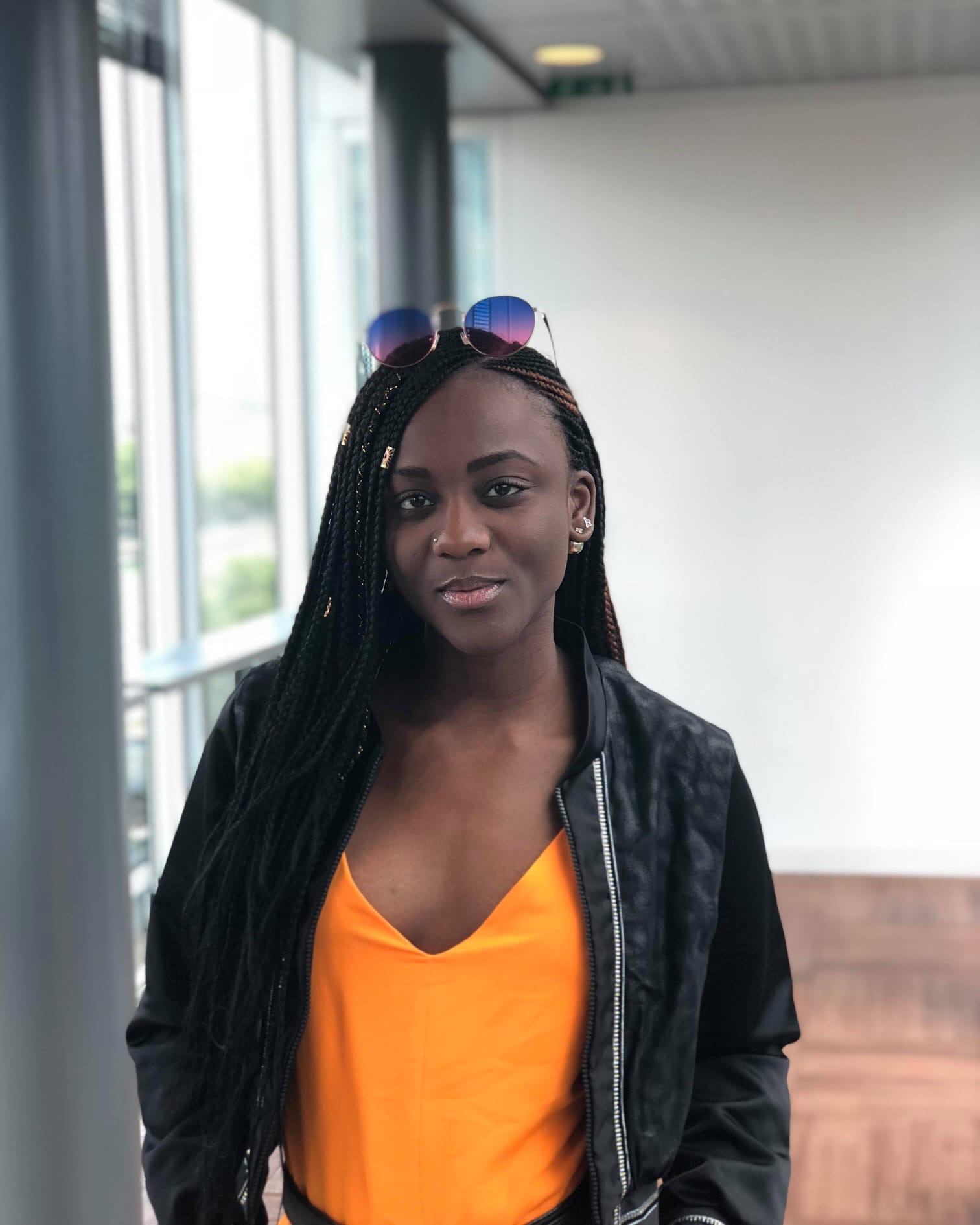 Femme portant un top orange Wax.by.Mona sous une veste noire